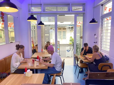 Diners at wooden tables inside Bao Bao, with the street visible through the front windows