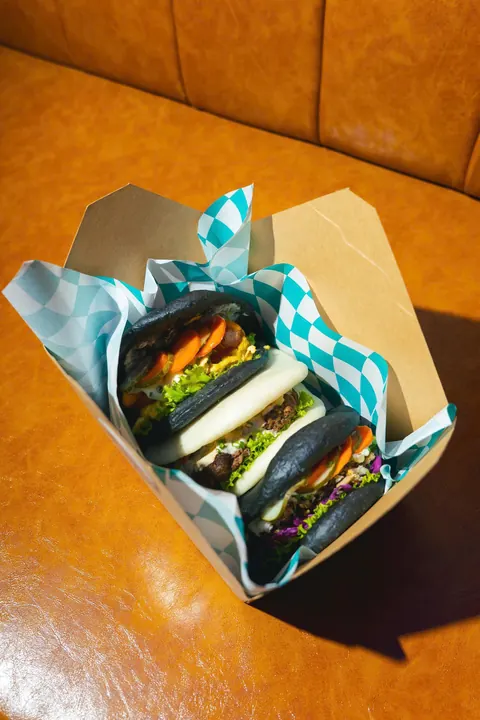 Three bao packed in a takeaway box lined with turquoise checked paper